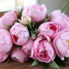 A bouquet of pastel peonies on a rustic table
