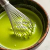 A bowl of matcha being whisked in a traditional bowl