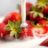 A close-up of a splash of milk hitting fresh strawberries