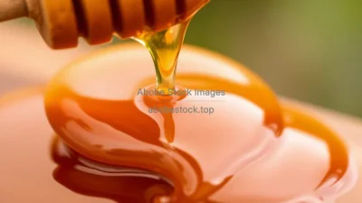 A close-up of honey dripping from a wooden dipper