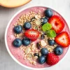 A colorful smoothie bowl topped with berries and seeds