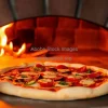 A freshly baked pizza coming out of a brick oven