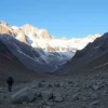 A mountain valley once snowy now dry with exposed rocks hikers looking concerned