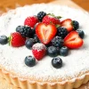 A rustic tart topped with fresh berries and powdered sugar