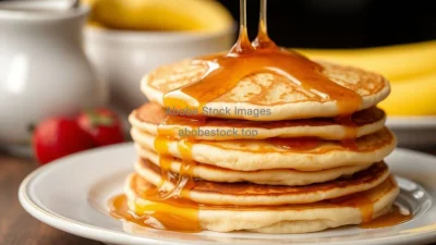 A stack of fluffy pancakes with maple syrup dripping