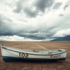 A stranded fishing boat on a dried lakebed under dramatic clouds environmental crisis image