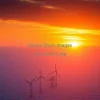 A sunset over a wind farm in the ocean