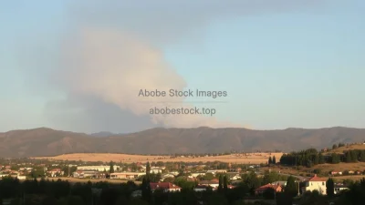 A wildfire smoke plume reaching high into the sky seen from a nearby town