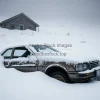 Abandoned car half buried in snow near a mountain cabin bleak atmosphere