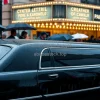 Black limousine waiting outside a theater premiere raining umbrellas crowds