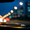 Car dashboard close up with reflections of city lights on windshield