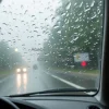 Car driving through heavy storm rain hitting windshield view from inside