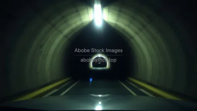 Car entering a dark tunnel with bright light at the far end sense of journey