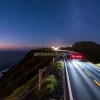 Car on a cliff edge road overlooking the ocean long exposure starry sky