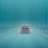 Car on a foggy bridge cables disappearing into mist melancholic feel