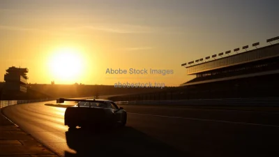 Car on a racetrack at sunrise pit building silhouettes warm backlight
