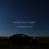 Car parked under a glowing full moon in open countryside starry sky