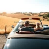 Classic convertible with couple inside driving through Italian countryside