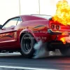 Drag racing car launching from starting line flames from exhaust intense action