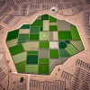 Drone shot of a patchwork of green regenerative farms surrounded by barren land contrast