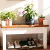 Entryway bench with shoes underneath and top decorated with plants and flowers