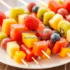 Fresh colorful fruit skewers arranged on a white platter