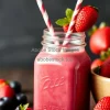 Healthy berry smoothie in a mason jar with paper straw