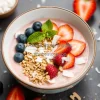 Healthy smoothie bowl decorated with fruit granola and coconut flakes