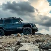 Luxury off road vehicle on rocky mountain terrain cloudy dramatic sky