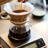 Pour-over coffee in ceramic dripper on scale