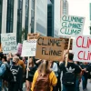 Protesters marching for climate action holding signs in a modern city street high contrast