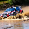 Rally car splashing through a river crossing mud and water flying