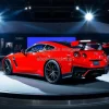 Red sports car showcased on a rotating platform at an auto show spotlights