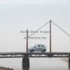 Small car crossing an old metal bridge over a river foggy morning