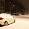 Snow covered car parked on a quiet suburban street during heavy snowfall winter mood