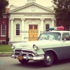 Vintage police car in front of an old courthouse nostalgic scene